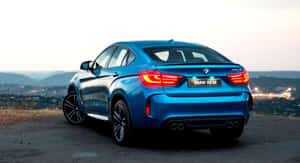 藍色BMW X6 M跑車停在俯瞰城市景觀的山丘上，在黃昏時分。 — 寶馬X6 M 壁紙