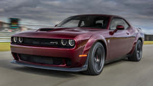 栗色 Dodge Challenger SRT 喺賽道上高速行駛，帶有動態模糊效果。