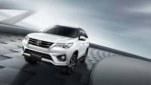 白色豐田 Fortuner SUV 在未來感灰色平台上，帶有戲劇性燈光。