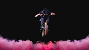 Bmx車手在黑色背景上跳過粉紅色煙霧 — Studio Display 壁紙