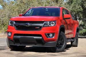 紅色雪佛蘭 Colorado Z71 皮卡車停在樹旁的泥土上。