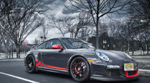 灰色保時捷911 GT3 RS，帶紅色點綴，停在光禿樹木和陰天下的街道上。