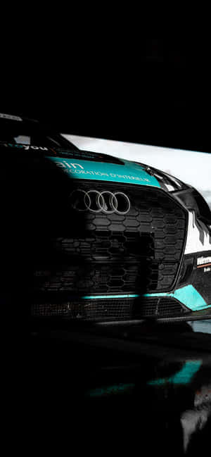 Audi 賽車前格柵特寫，帶有青綠色點綴和碳纖維紋理。