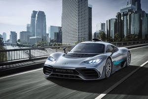 銀色 Mercedes-AMG 跑車在都市大橋上飛馳，背景有摩天大樓。