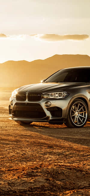 銀色BMW X6 SUV停泊喺金色夕陽下嘅沙漠。 — 銀河A 壁紙