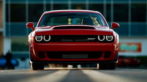 紅色Dodge Challenger SRT面向鏡頭，在日落時分帶有發光的頭燈。