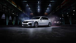 白色BMW M5房車在黑暗的工業倉庫中，帶有煙霧和聚光燈。