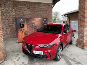紅色 Alfa Romeo Tonale 電動 SUV 插入磚砌建築附近的充電站。