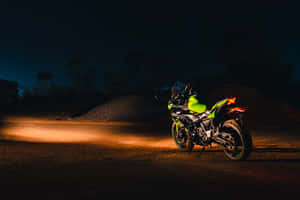 螢光綠色電單車在夜間停在碎石路上，車頭燈亮著。