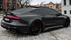 啞光黑色奧迪RS7 Sportback，帶紅色點綴，停在鵝卵石街道上。 — 奧迪 GIF 壁紙