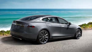 銀色Tesla Model S停泊在沿海碎石路上，享有海景。 — Tesla GIF 壁紙