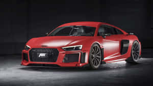 啞光紅色ABT Audi R8跑車在黑暗車庫中，聚光燈照射。