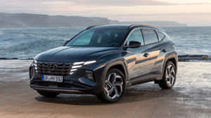 深灰色現代 Tucson SUV 停泊在日落時分近海的濕滑海岸公路上。