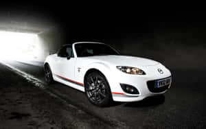 白色Mazda MX-5開篷跑車駛出黑暗隧道進入明亮光線。