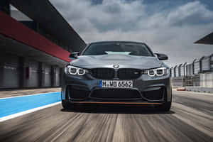 一輛灰色BMW M4在賽道上加速行駛，帶有動態模糊效果。