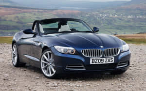 深藍色BMW Z4開篷跑車停泊在風景優美的山坡上，俯瞰著景色。