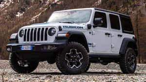 白色Jeep Rubicon停放在靠近雪山的多岩石地形上。