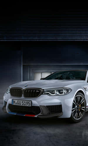 銀色BMW M5跑車停放在黑暗的工業車庫中。
