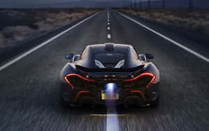黑色McLaren P1在黃昏時分在沙漠高速公路上飛馳，帶有發光燈光。