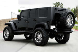 黑色Jeep Wrangler配鉻合金輪胎停在路面上。