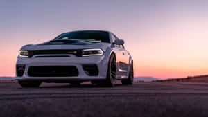 白色Dodge Challenger SRT Hellcat在日落時停泊在沙漠公路上。