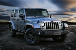 日落時分，銀色Jeep Wrangler停在裂開的瀝青上。
