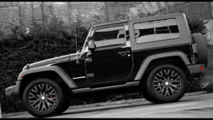 黑色Jeep Wrangler停泊在靠近磚牆和綠化的城市街道上。