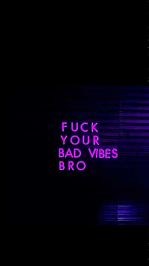 霓虹招牌寫着 'FUCK YOUR BAD VIBES BRO' 在黑暗中發出紫色光芒。