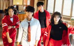 四個穿著紅色運動服和校服的青少年站在課室裡。