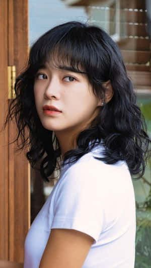 深色波浪髮年輕女性穿白色T恤在木門旁