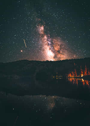 銀河系倒映在湖中，岸邊夜晚有發光的樹木。