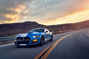 藍色 Shelby Mustang GT500 在日落時分在沙漠高速公路上疾馳。
