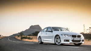 金色夕陽下，白色BMW房車在蜿蜒的山路上。