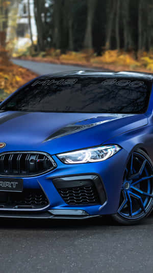 啞光藍色BMW M8跑車停在秋天的森林道路上。