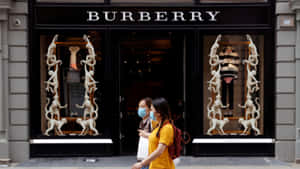 兩名戴著口罩的女性經過一間Burberry商店，櫥窗內有猴子雕塑。
