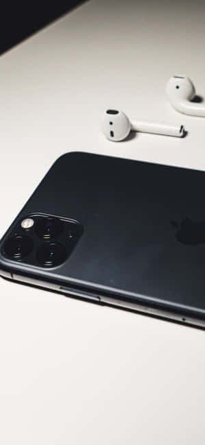 黑色iPhone和白色耳機在白色桌面上。