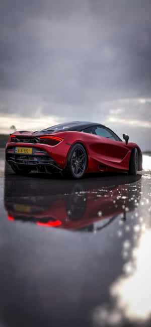 紅色McLaren跑車在濕路上，帶有戲劇性的天空倒影 — iPhone 15 Pro 壁紙