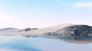 平滑的沙漠沙丘在柔和天空下倒映在平靜的藍色海水中。