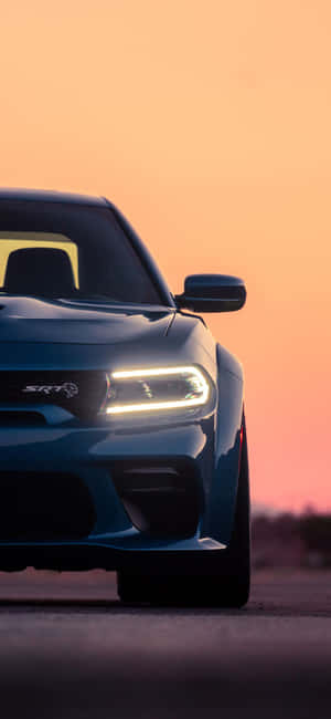 藍色Dodge SRT汽車在日落時分於道路上亮起車頭燈。