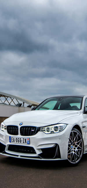 白色BMW M4跑車在戶外多雲天空下停泊，靠近現代建築。 — Redmi Note 13 Pro 壁紙