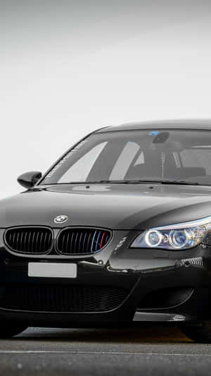 黑色BMW M5跑車，帶有發光的頭燈和M條紋。