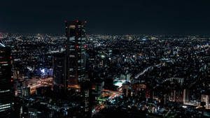 密集市區的夜間高空照片，建築物和街道閃閃發光。 — 夜景城市 壁紙