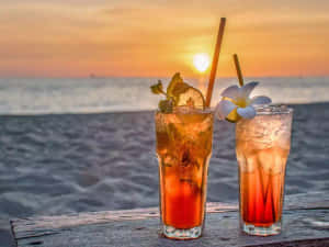 沙灘上兩杯冰凍雞尾酒，背景是海洋日落
