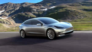 銀色Tesla Model 3在白雪覆蓋的山峰和翠綠山丘的山路上行駛。 — Tesla GIF 壁紙