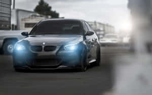 銀色BMW M5轎車，頭燈明亮，停放在城市空地中。