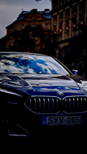 黑色BMW汽車，帶有天空和雲朵的倒影，停放在歷史建築附近。 — 9:16 壁紙