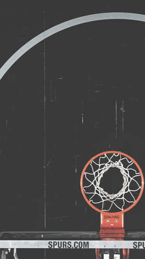 在深色球場上帶有Spurs.com品牌的籃球框和網。