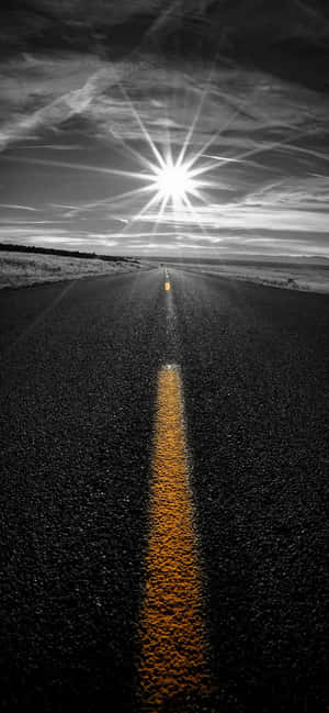 在明亮太陽下的一條長直道路，帶有黃色中心線。