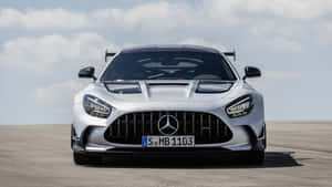 銀色 Mercedes-AMG GT R 賽車喺鋪砌嘅賽道上，喺多雲嘅天空下。
