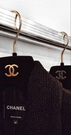 黑色 Chanel 服裝掛在金色衣架上，帶有可見的品牌標籤。